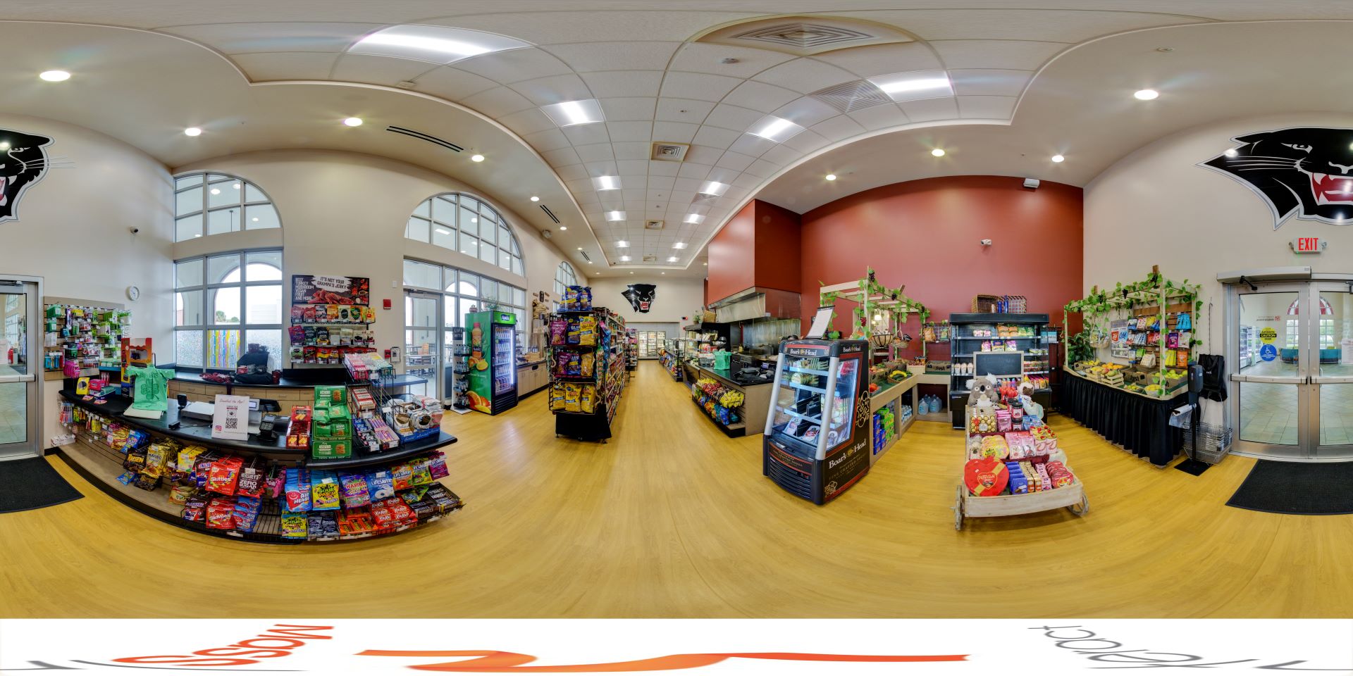 Panoramic view of a well-stocked college grocery store with various snacks, drinks, and other items displayed on shelves and coolers